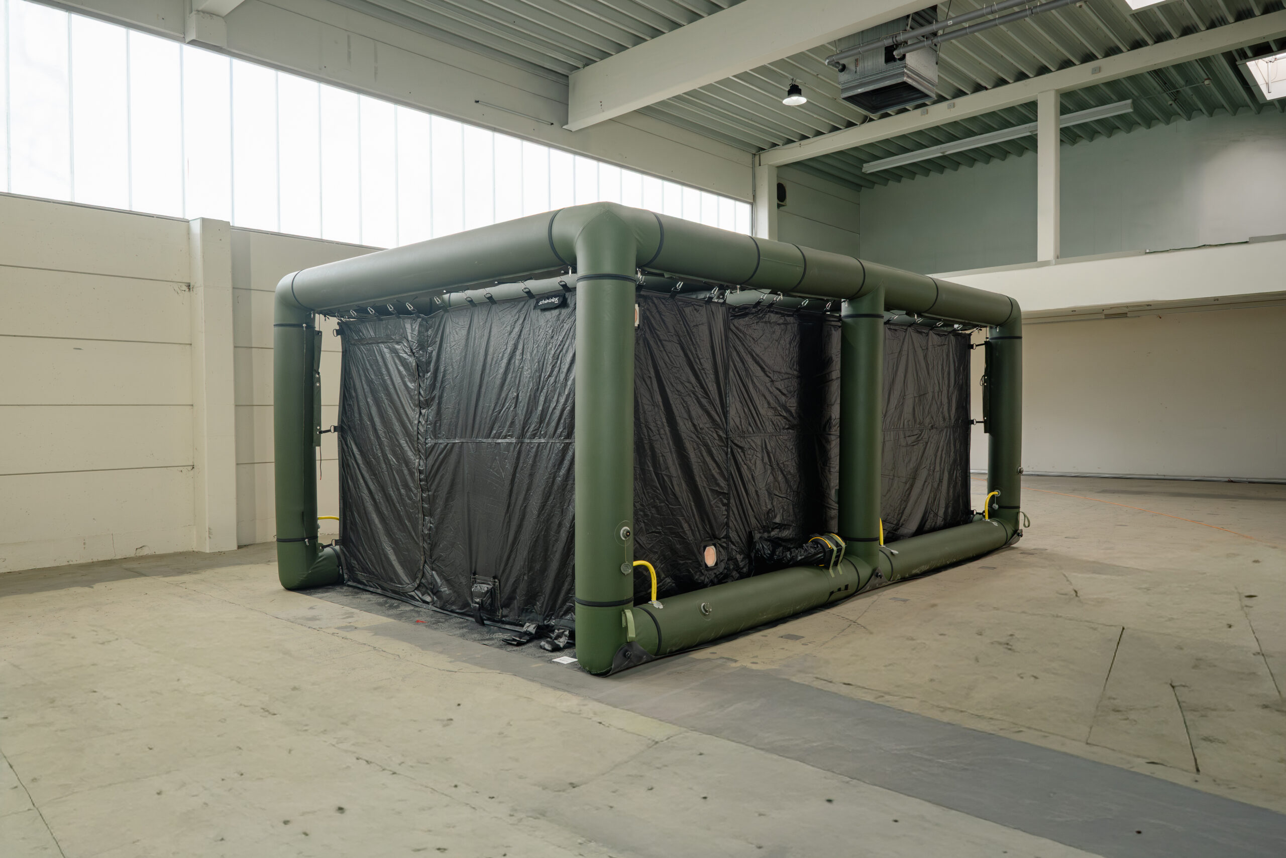 Aufgebautes Zeltsystem mit aufblasbarer Rahmenkonstruktion und geschlossener Zeltwand in einer Halle.